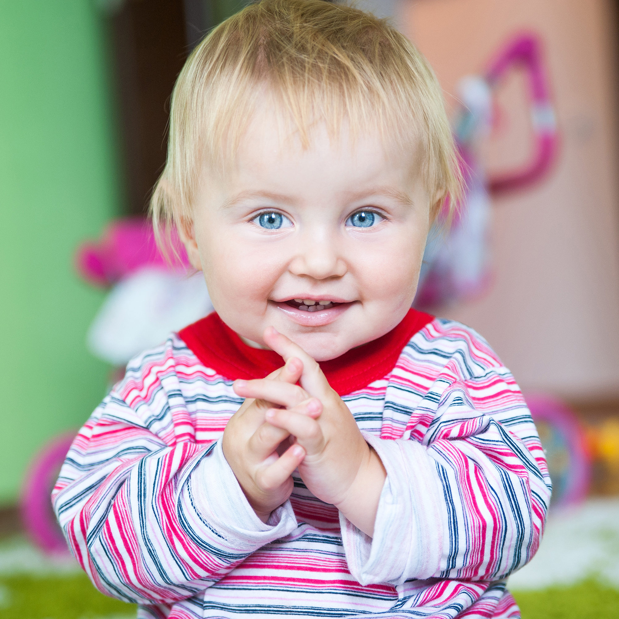 cute blue-eyed toddler in the nursery close-up claps